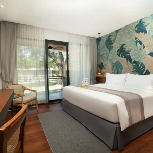 Interior of a hotel room with a bed, a television, a desk, and a chair, showcasing a cozy atmosphere.