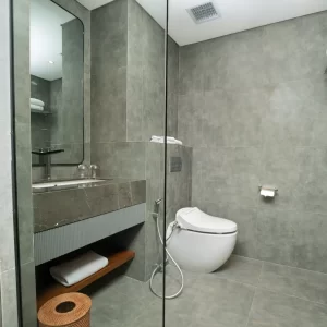A bathroom featuring a toilet, sink, and shower, designed for functional and efficient use of space