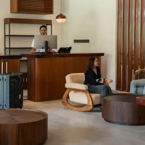 A group of people seated at a desk in a lobby, engaged in conversation and interacting with each other