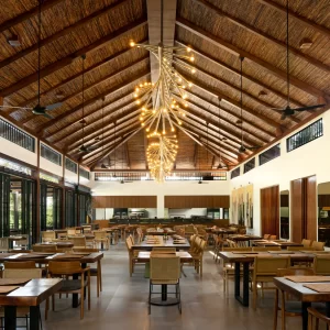 Interior of a restaurant with wooden ceilings and multiple tables set for guests.