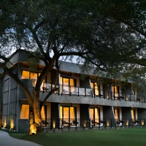 Night view of House Sira Lombok resort, illuminated with lights, surrounded by trees and lush grass.