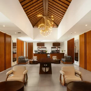 An expansive lobby in a clubhouse, adorned with a grand chandelier and multiple pieces of stylish furniture.