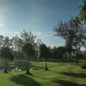 A picturesque golf course surrounded by trees, with a serene body of water enhancing the landscape.