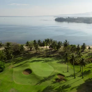A picturesque sira beach golf course with green trees and a serene water view in the distance.